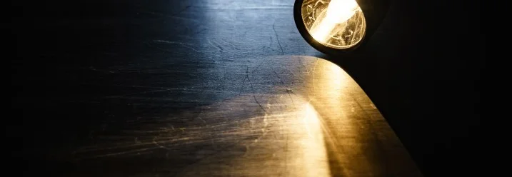 Eingeschaltete Taschenlampe leuchtet auf Holzboden